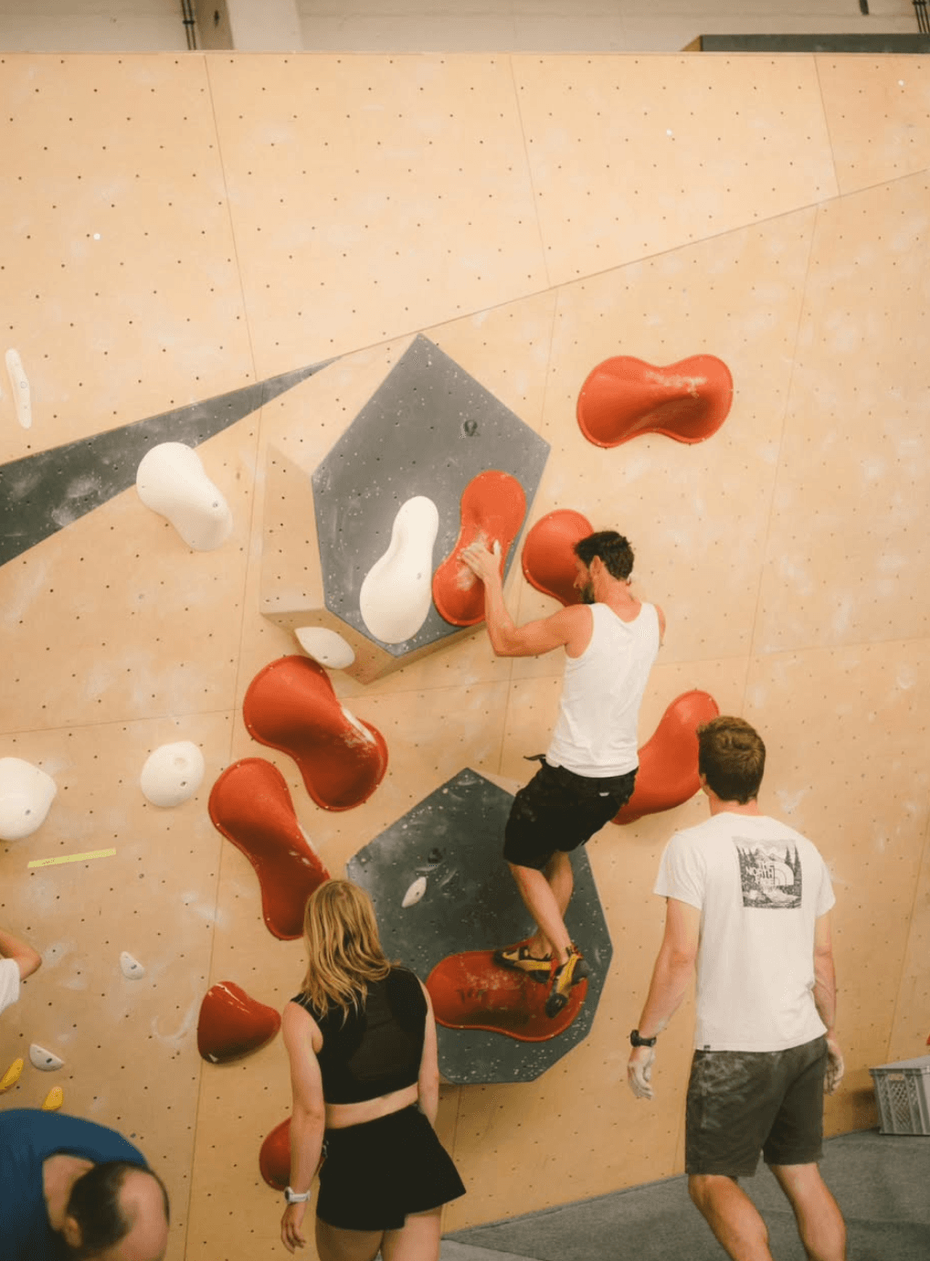 Boulderer im dynamischen Zug an roten und weißen Volumen
