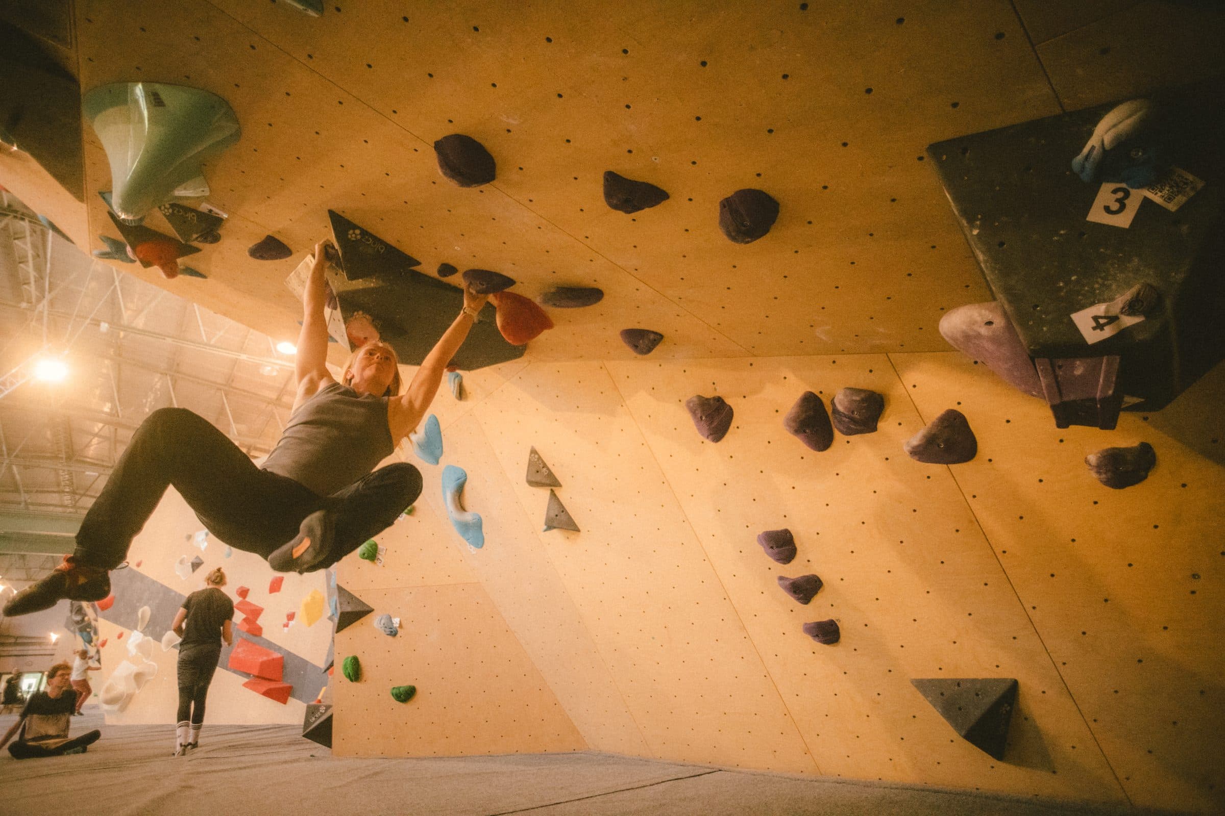 Boulderer hängt im Überhang zwischen dunklen Griffen